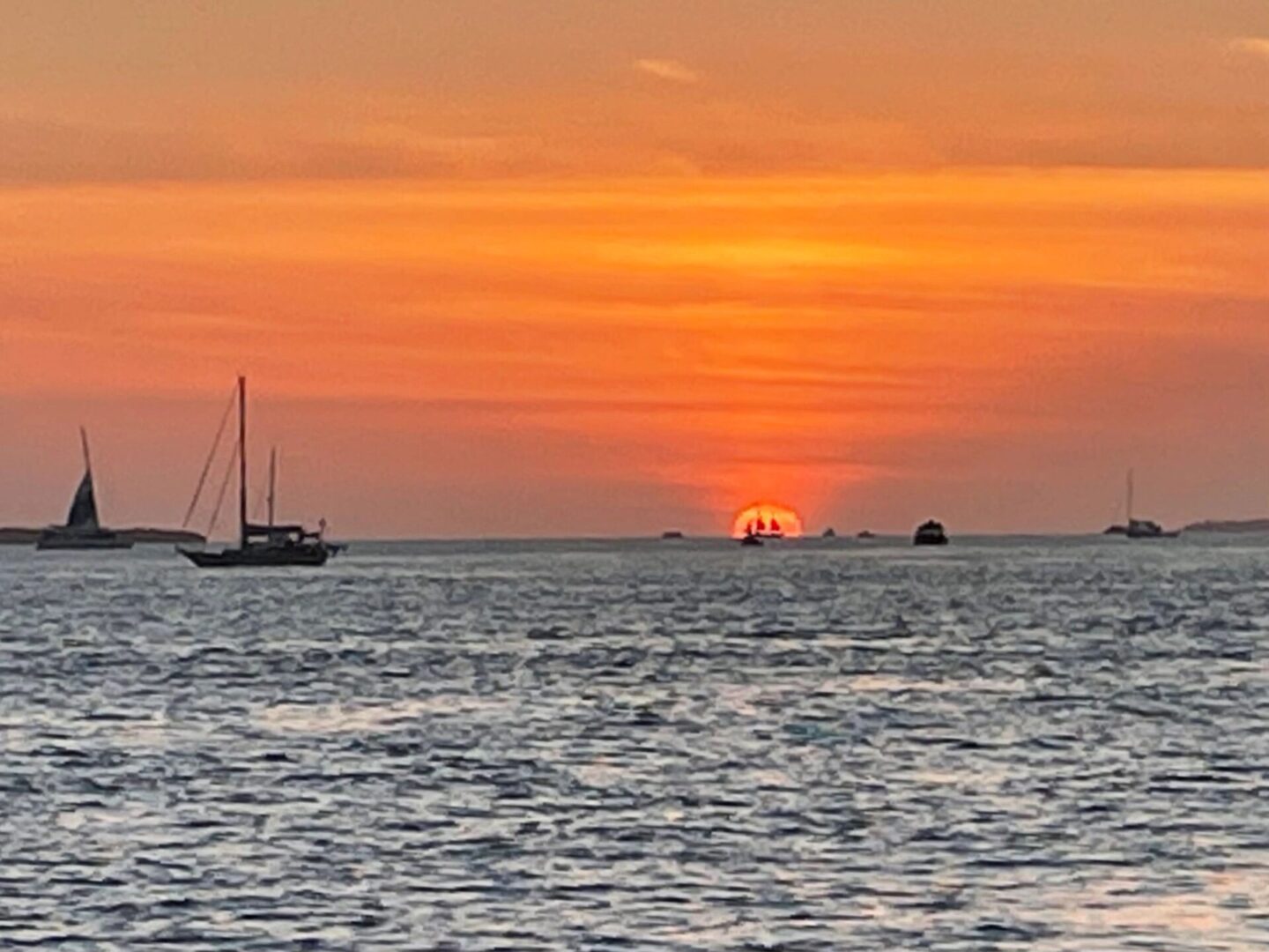 A sunset over the ocean with boats in it.