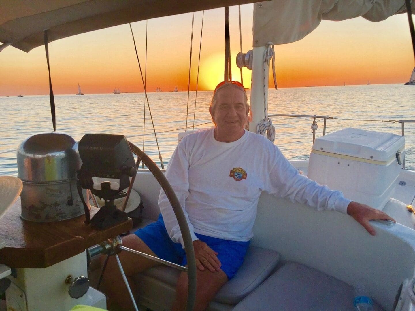 A man sitting on the deck of a boat at sunset.