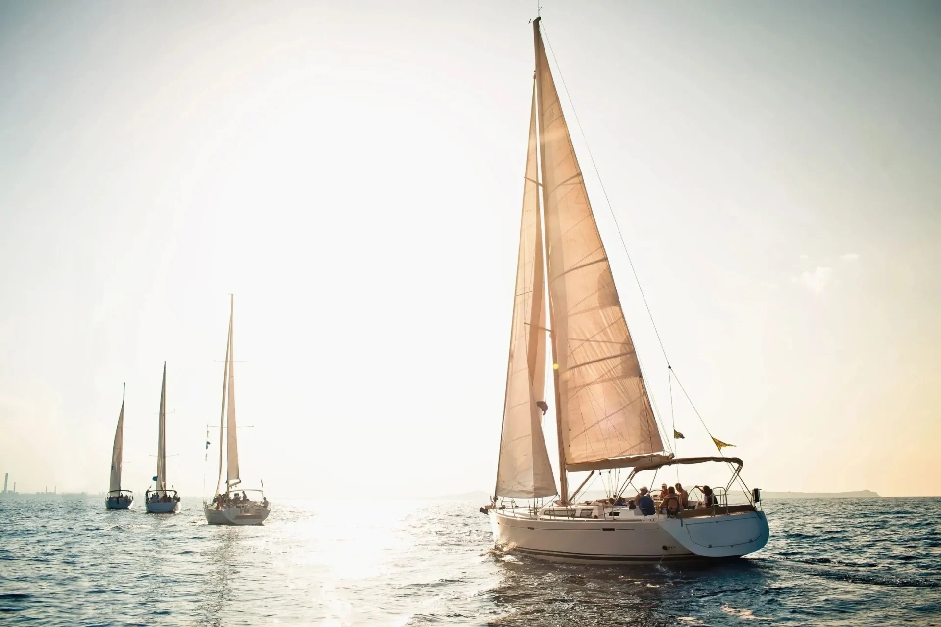 A group of sailboats in the ocean on a sunny day.