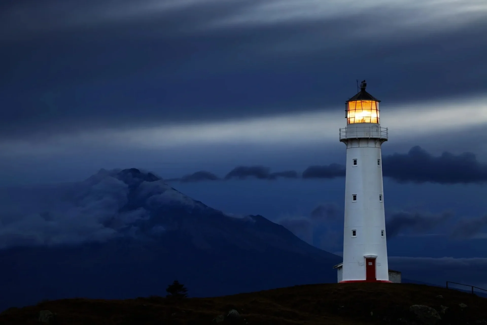 A light house is lit up at night.